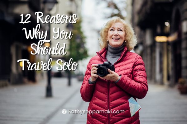 12 Reasons Why You Should Try Solo Travel blog post title with picture of a woman standing out on a street holding a camera