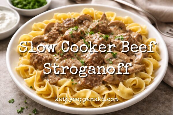Slow Cooker Beef Stroganoff blog post title with photo of a plate of beef stroganoff over pasta and green beans. They are on a white square plate sitting on a table top.